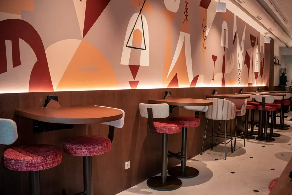 Sala de 5 Gallos con mesas altas y mural geométrico