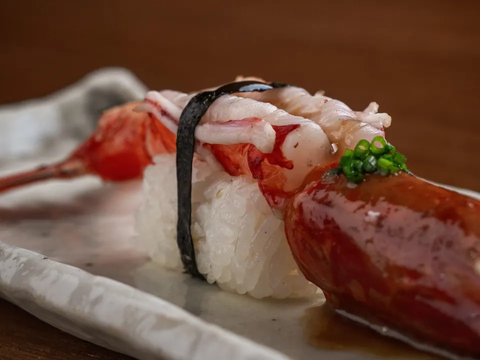 Nigiri templado con marisco sobre arroz y alga nori en primer plano
