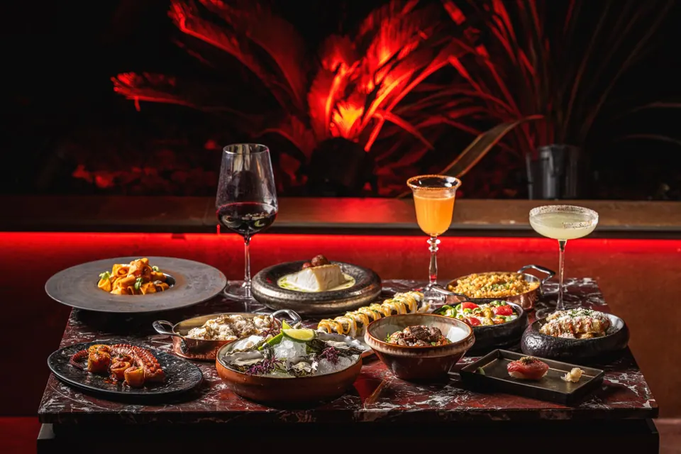 Mesa con platos para compartir, vino y cócteles en Bonbonniere Marbella