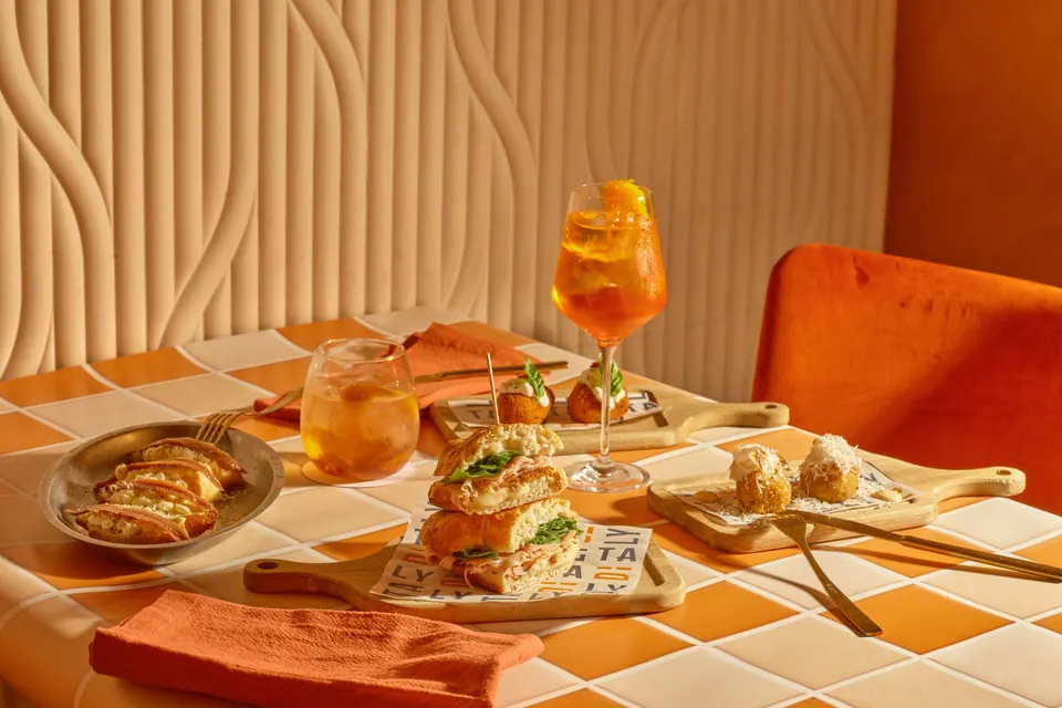 Mesa con focaccia, croquetas, montadillos y dos cócteles en Ditaly