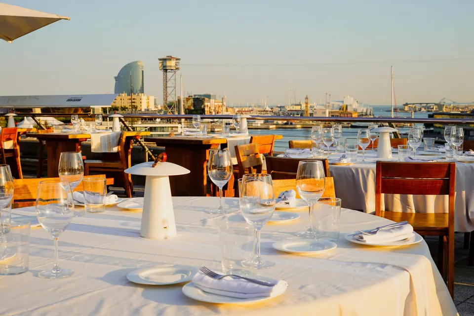 Terraza de 1881 con mesas montadas y vistas al puerto de Barcelona