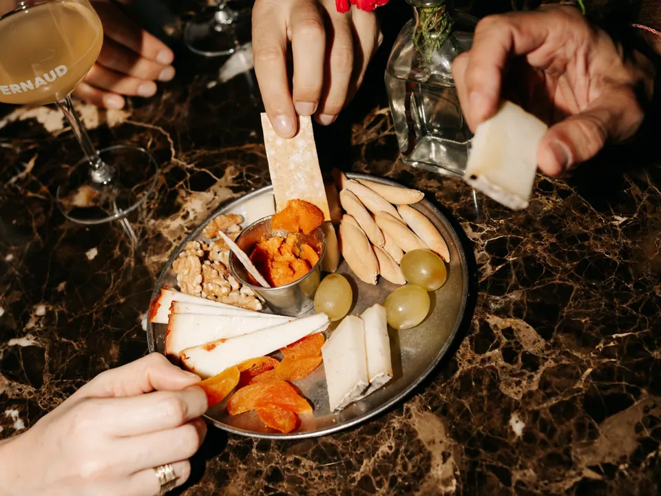 Tabla con quesos, uvas y aperitivos sobre mesa de mármol