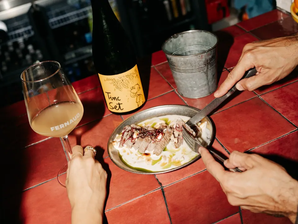 Plato para compartir y copa de vino en la barra de Fernaud