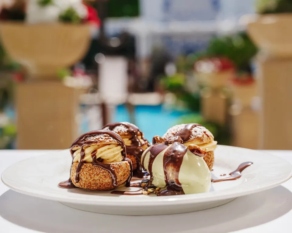 Profiteroles con salsa de chocolate y helado servidos en terraza