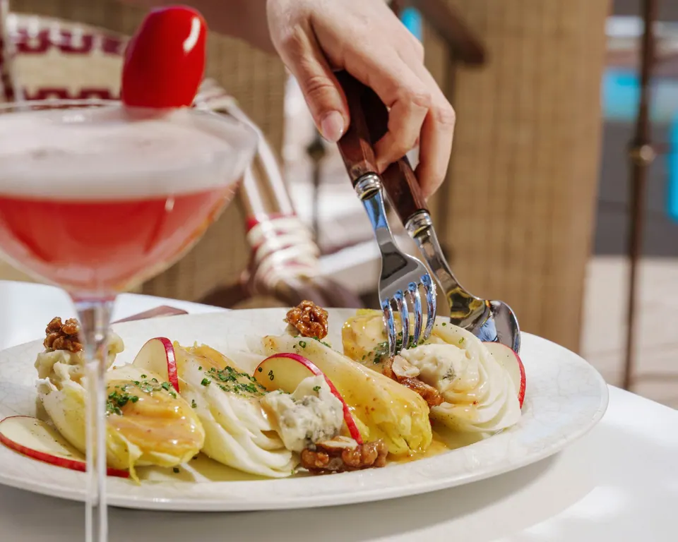 Ensalada de endivias con queso y nueces junto a un cóctel rosa