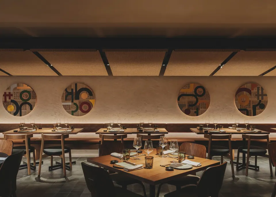 Sala interior de Nomo Eixample con mesas de madera y luz cálida