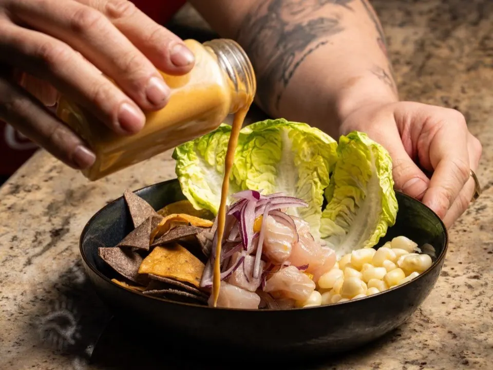 Preparación de un ceviche en sala con salsa y maíz