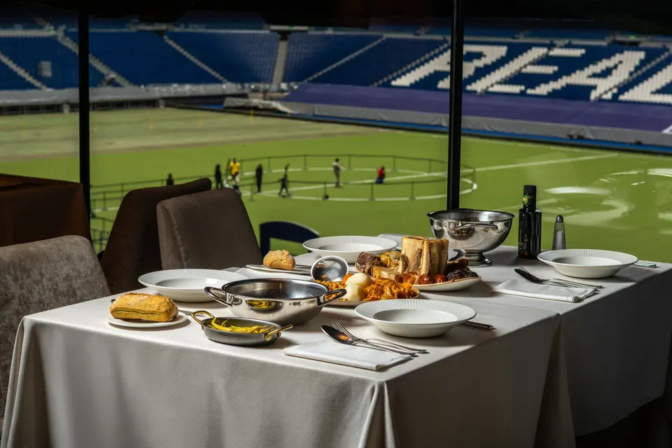Mesa con cocido servido junto al césped del estadio Bernabéu