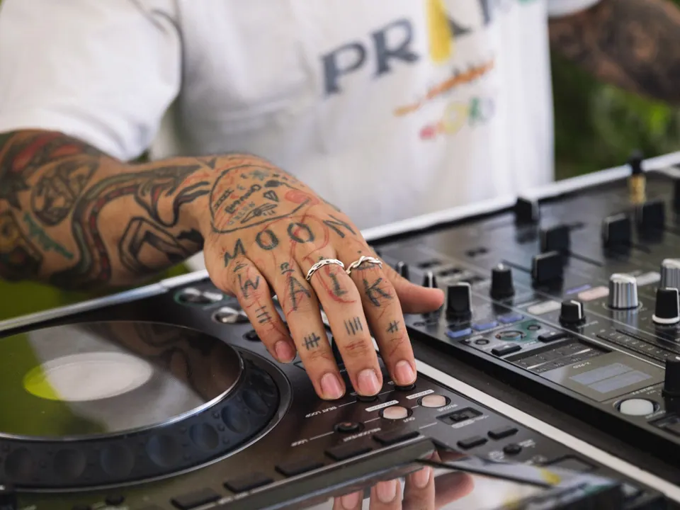 Primer plano de una DJ manejando la mesa de mezclas en un evento